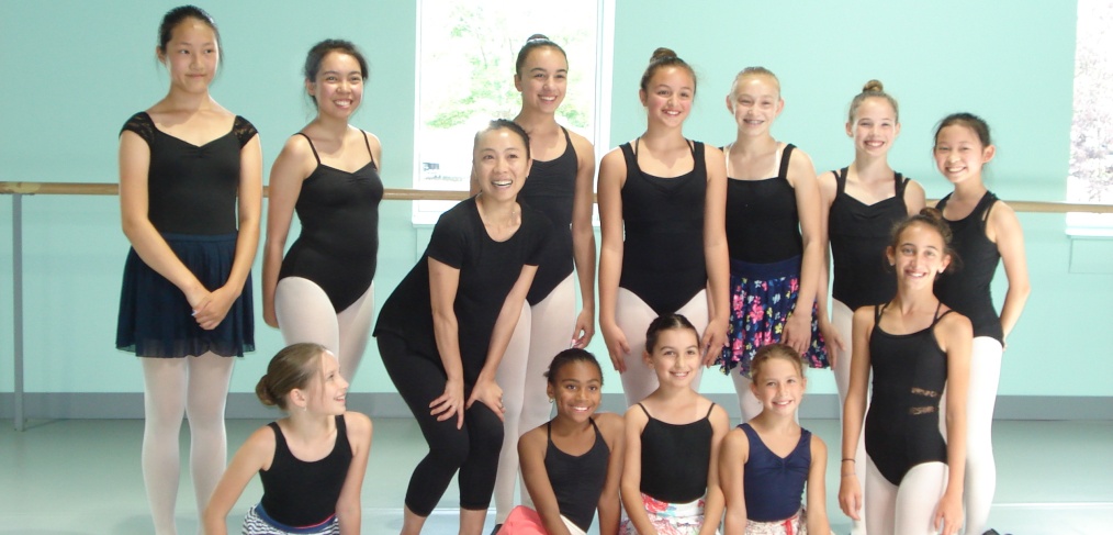 Group of young ballet dancers posing in a studio.