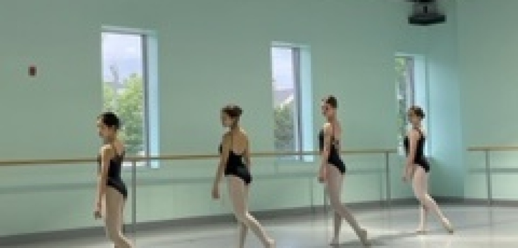 Four ballet dancers practicing in a studio with natural light.
